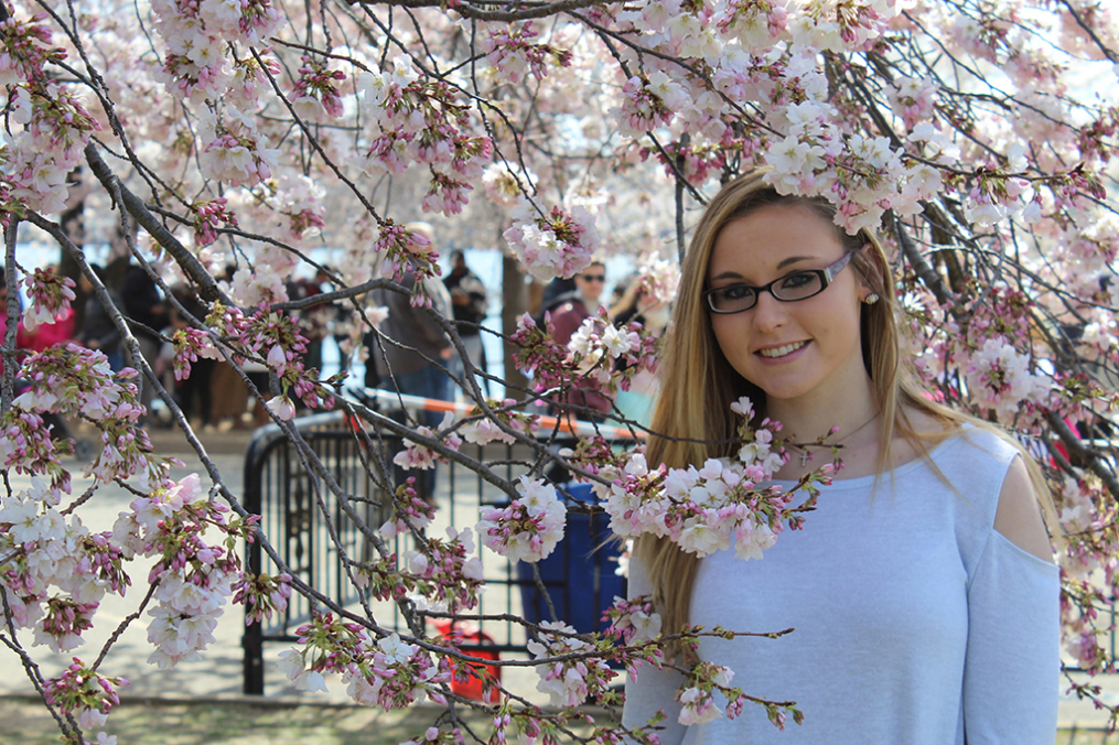 Ann Stull ’20 standing next to a tree with blossoms with the Norton Chapel in the background