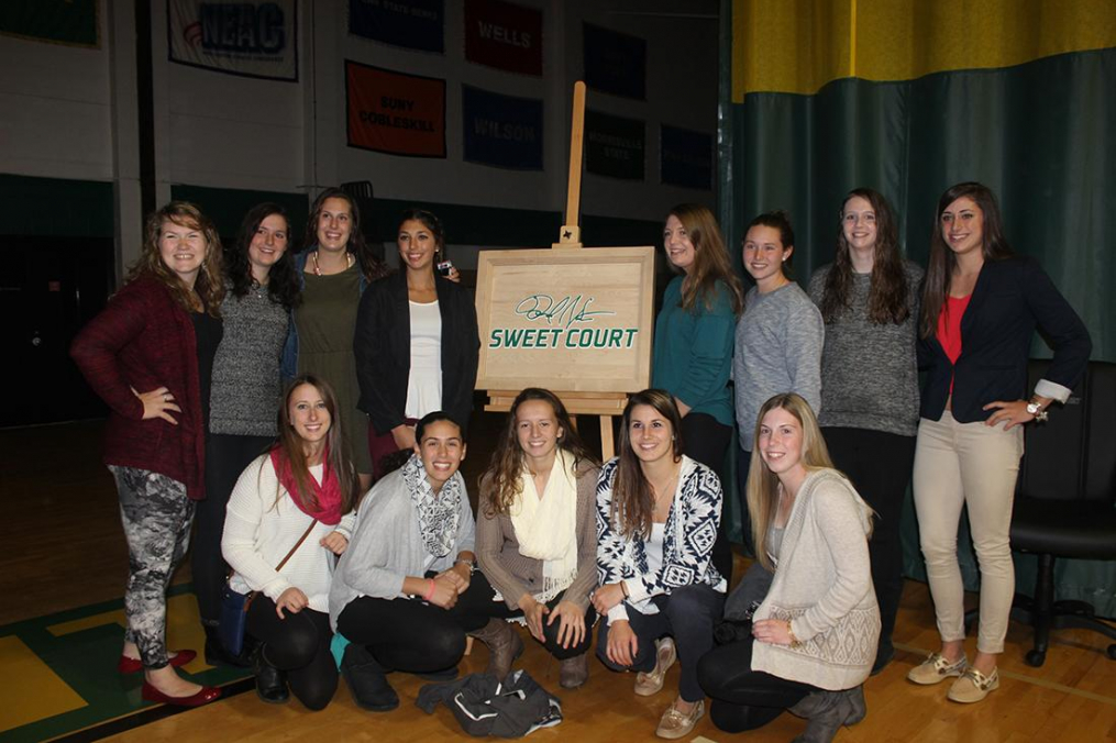A group of students stand with the David M. Sweet Court plaque.