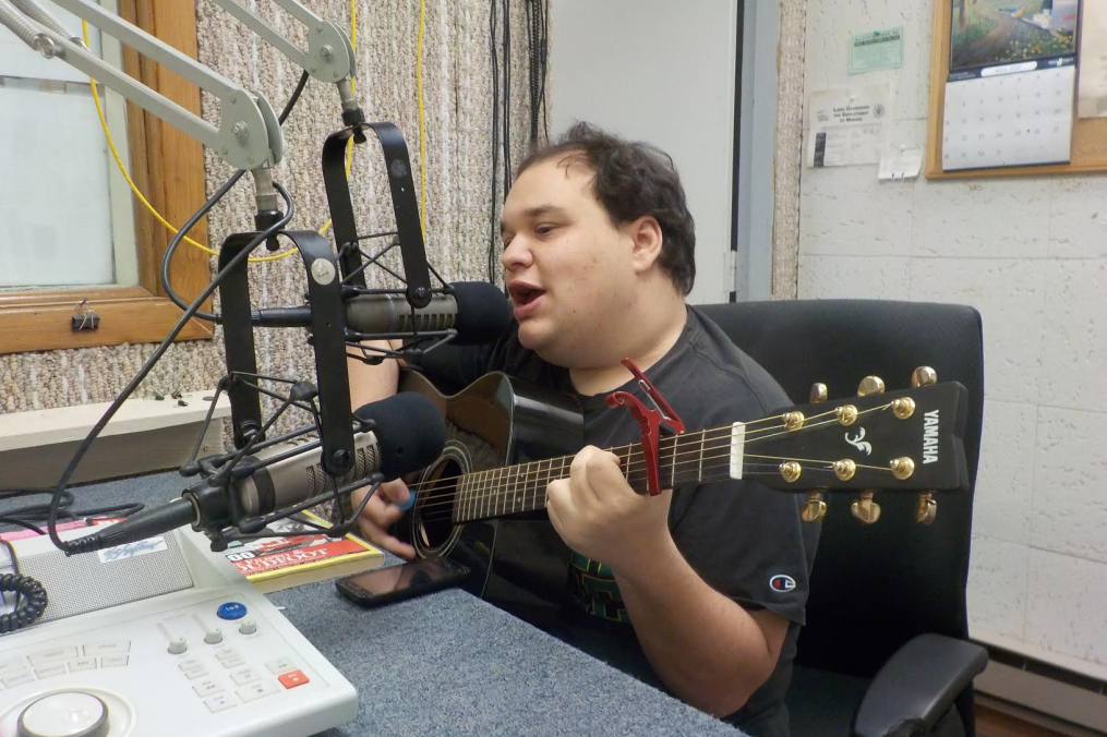 Chris Cahill singing with his guitar in a radio studio