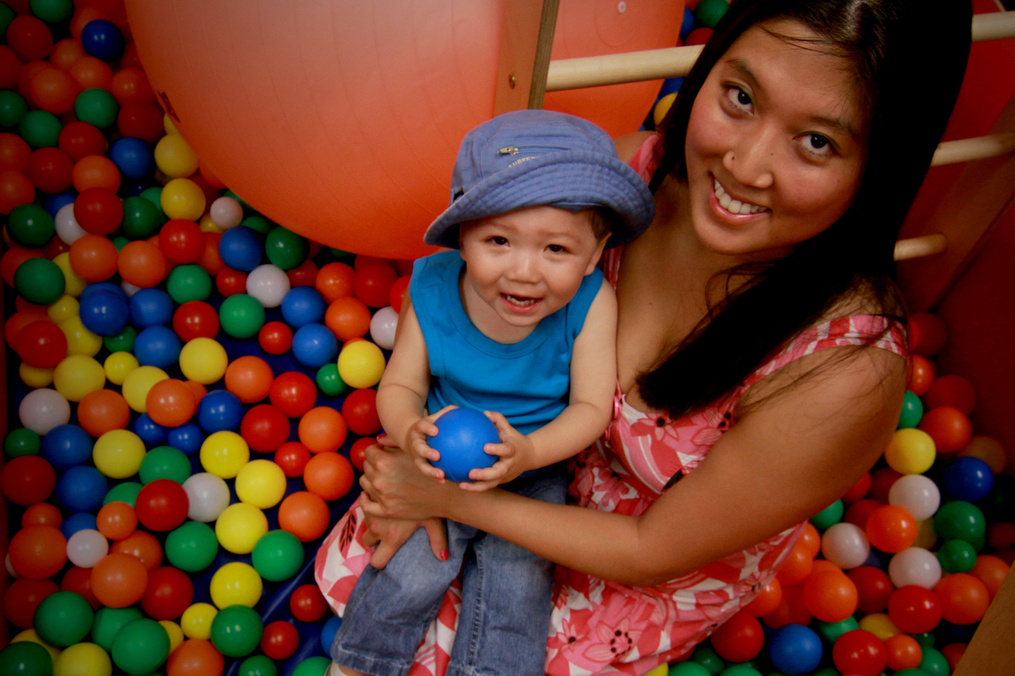 mom and child sitting in a container of colorful plastic balls