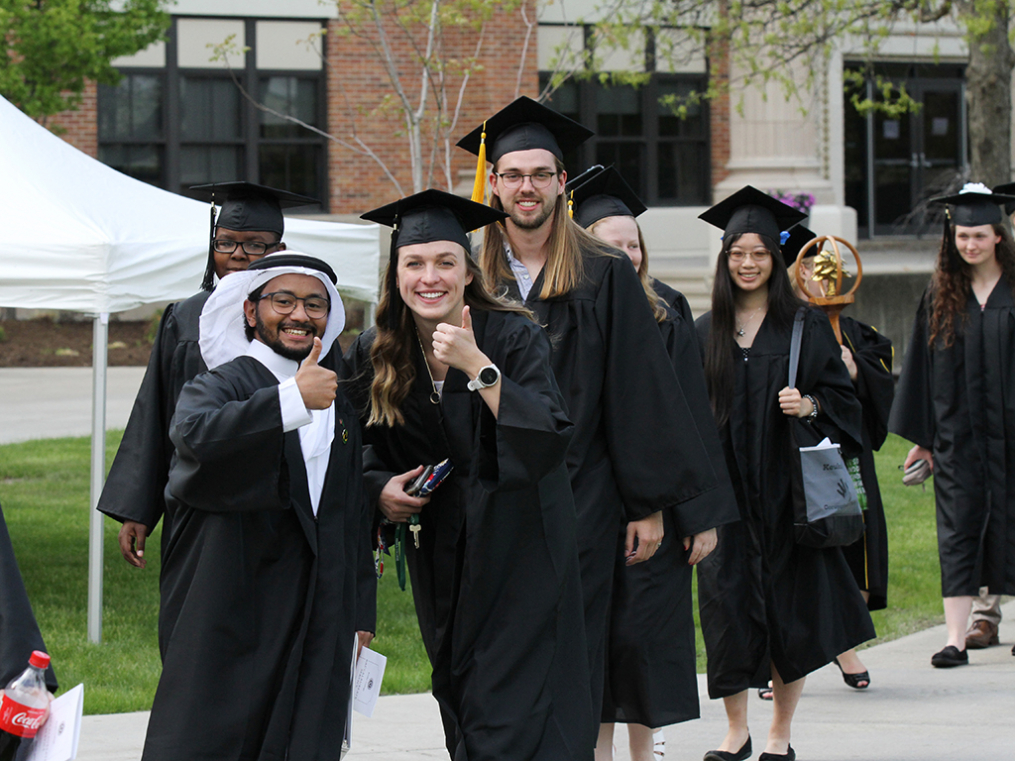 Graduating seniors Samy Hamdan, left, and Heather Chrisman pause to give a thumbs up as they head into the 2019 Baccalaureate Service, followed by Mack Ottens '19. 