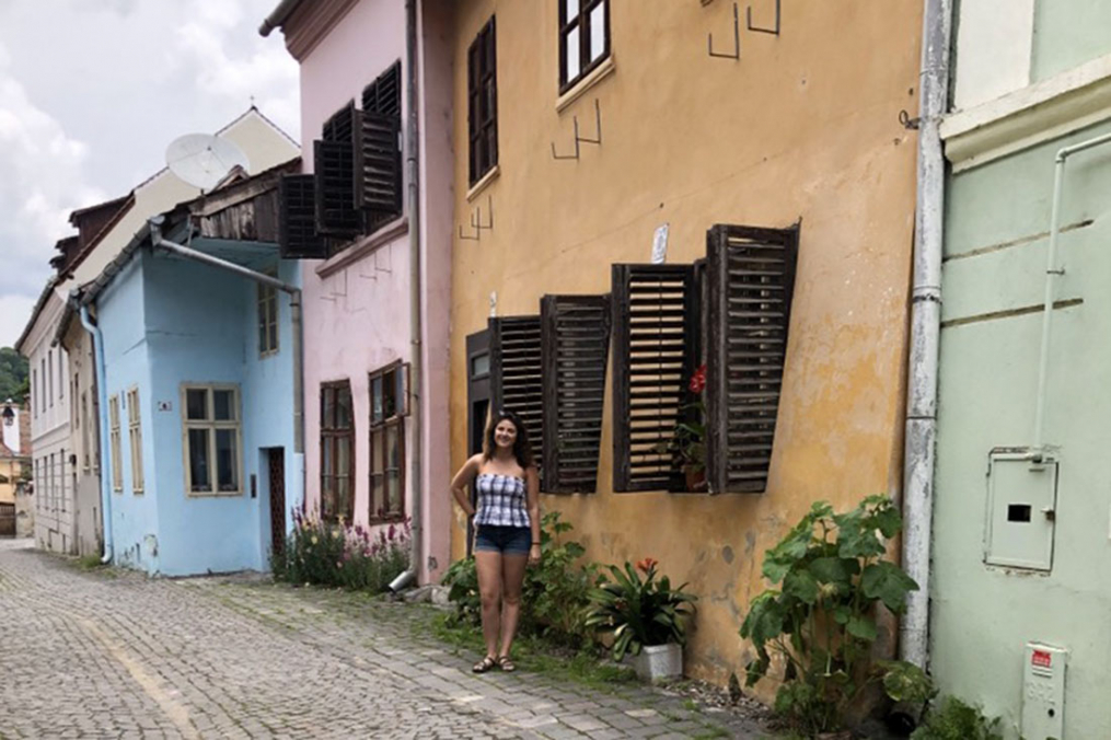 Ashley standing in front of houses and shops in Transylvania, Romania