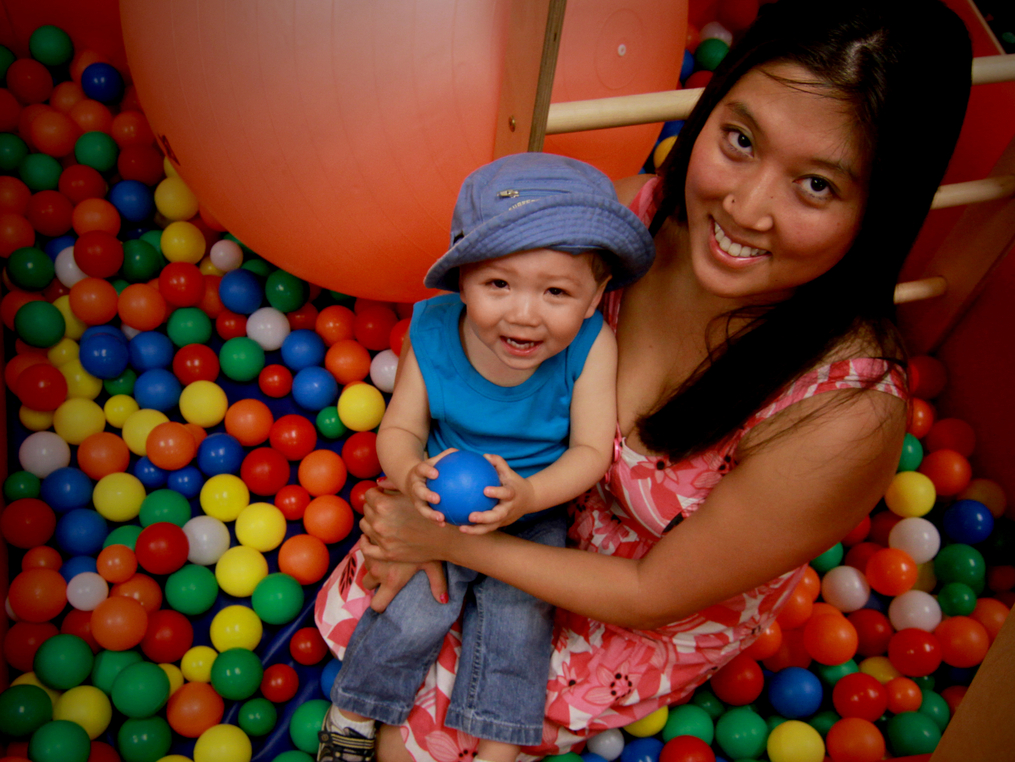 mom and child sitting in a container of colorful plastic balls